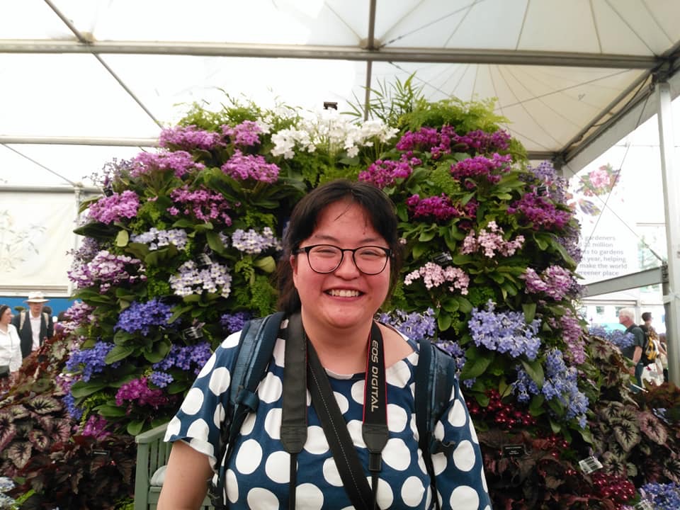 Piangfan standing with blue flowered shrub in the background